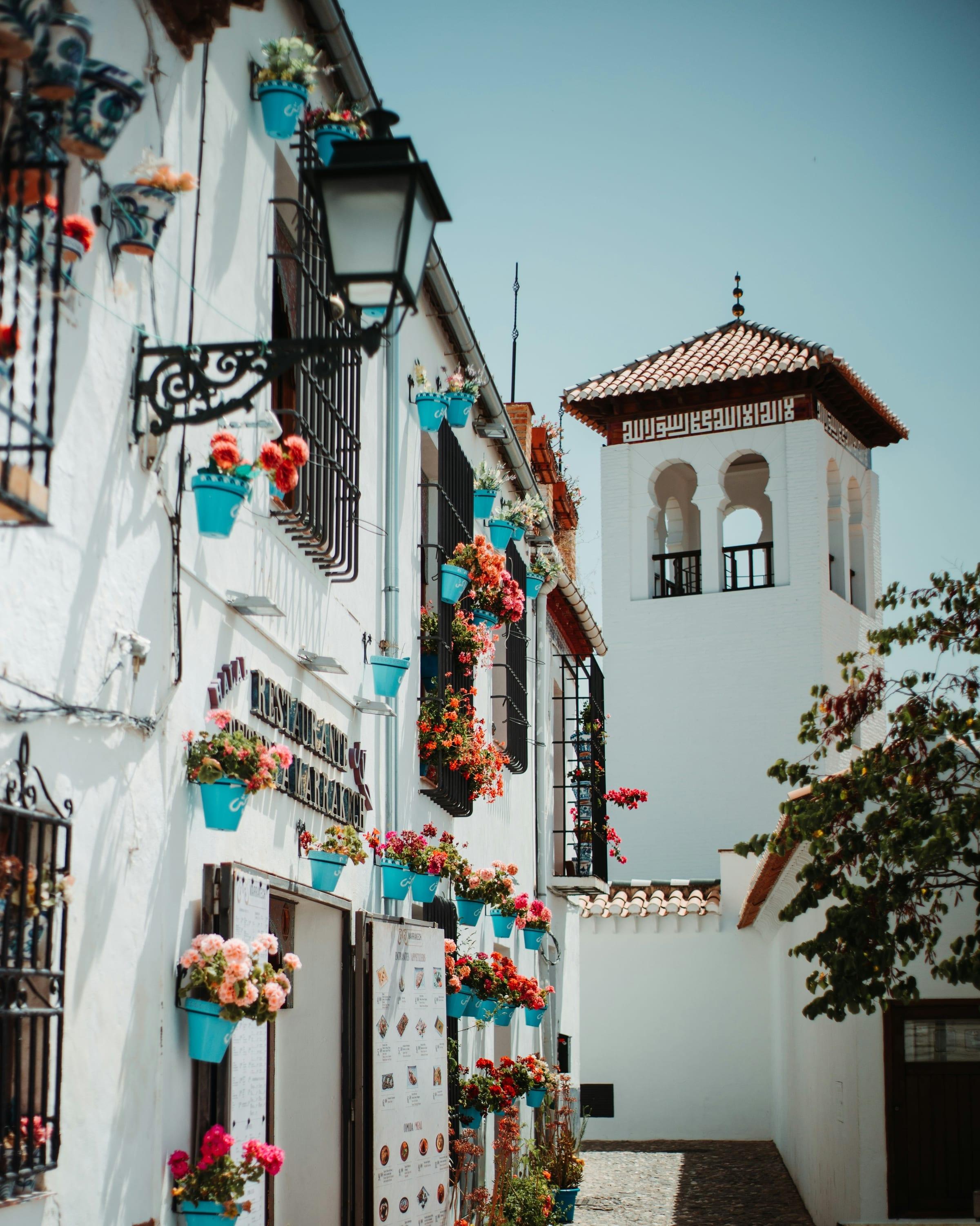 A whitewashed lane in the Albaicín hung with pots of red geraniums, a Moorish-style tower with a tiled inscription band rising behind the rooftops.